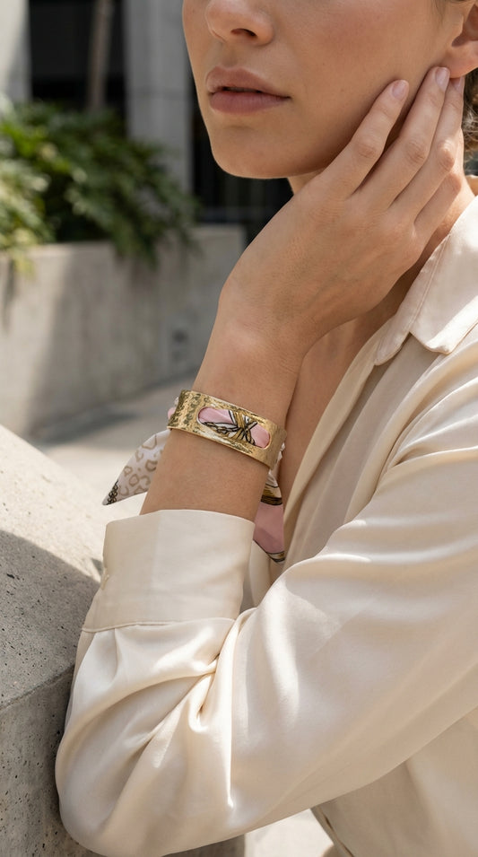 Gold bangle bracelet with a pink patterned silk scarf tie with rope print.